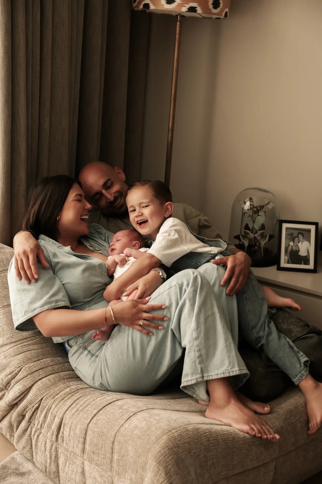 Lachend gezin met pasgeboren baby en grote broer op de bank, thuis